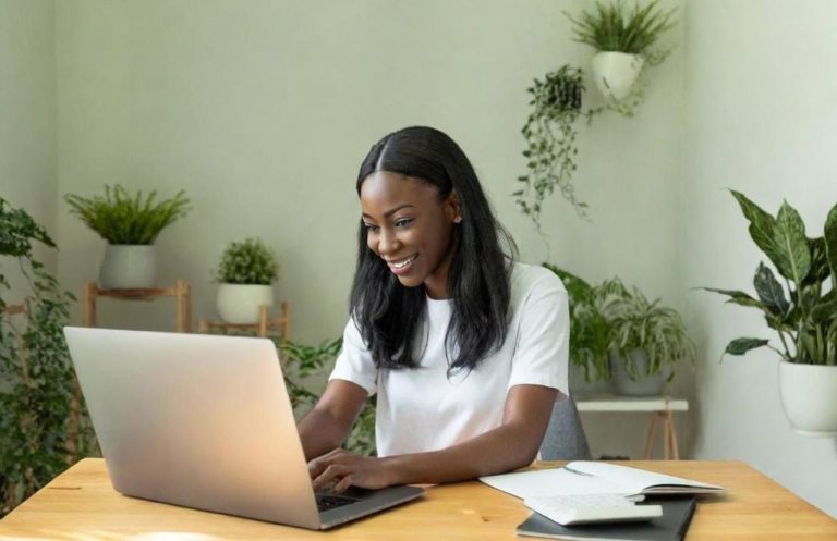 Femme travaillant sur un ordinateur dans son bureau Femme souriante travaillant sur un ordinateur portable dans un environnement verdoyant.
