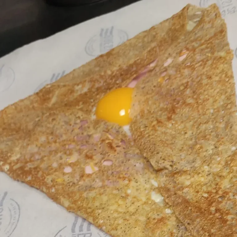 Galette complète réalisée en formation en Bretagne Galette bretonne croustillante avec un œuf au centre, servie sur du papier réalisée lors de notre formation en Bretagne